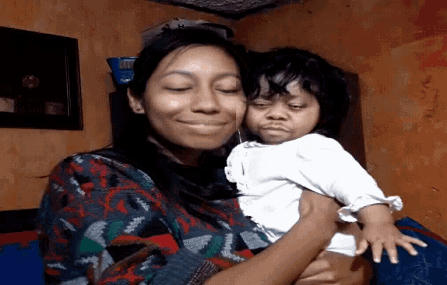 a woman is holding a baby in her arms and smiling for the camera