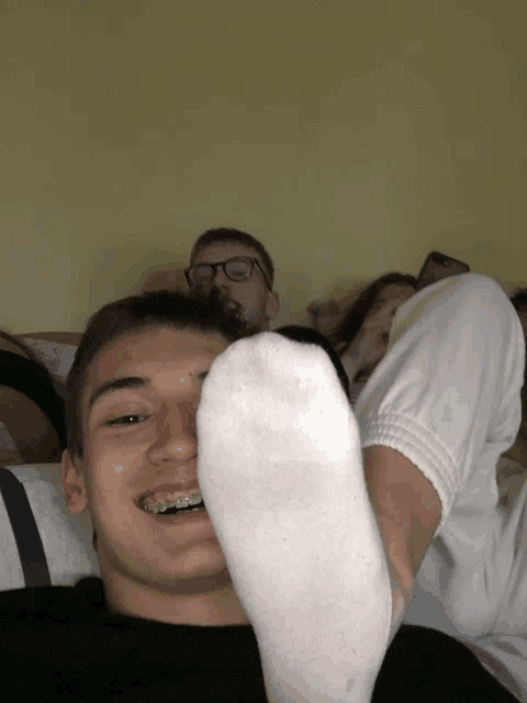 a boy with braces on his teeth is laying on a bed