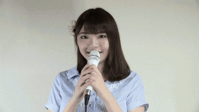 a woman in a blue and white striped shirt is holding a microphone