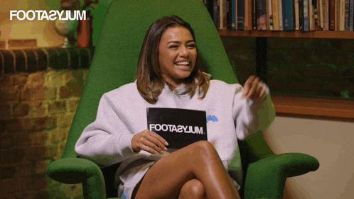 a woman sits in a green chair with a sign that says foota2yjum on it