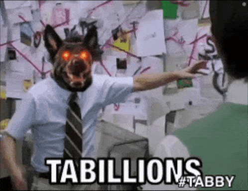 a man with a dog mask on his head says tabillions #tabby in front of a bulletin board