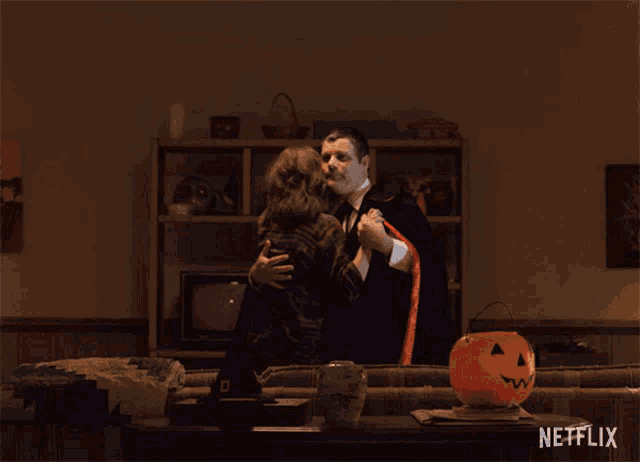 a man in a vampire costume is hugging a woman in a living room with a netflix logo in the corner