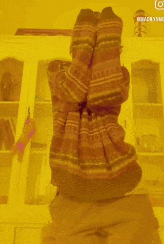 a person wearing a striped sweater covering their face in front of a cabinet