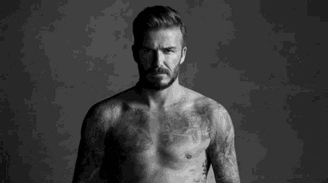a shirtless man with a tattoo on his chest is standing next to another shirtless man .