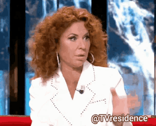 a woman with red hair is sitting on a red couch in front of a screen that says tvresidence