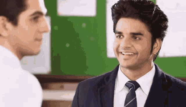 a man in a suit and tie talks to another man