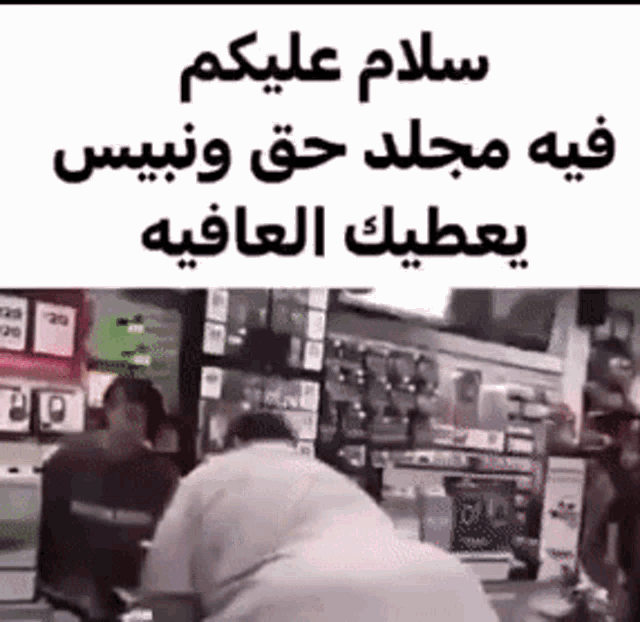a man is laying on the ground in front of a store with arabic writing on it .