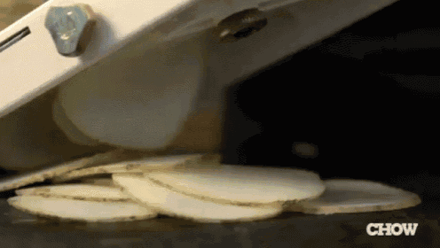 potatoes are being sliced in a machine with the word chow in the corner