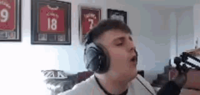 a man wearing headphones is singing into a microphone in a room .