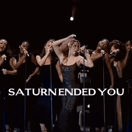 a group of people standing in front of a stage with saturn ended you written on it