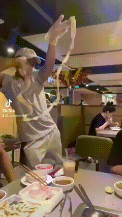 a man in a white shirt is holding a glove over his head in a restaurant ..