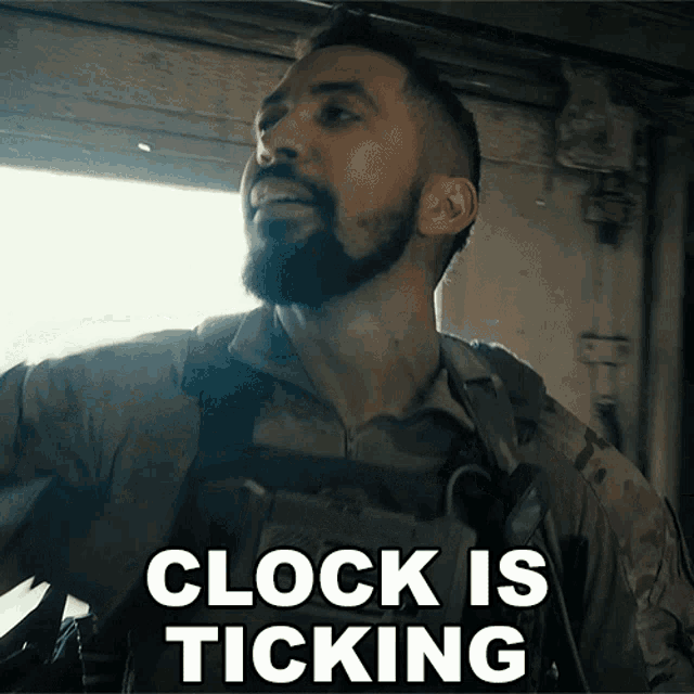 a man with a beard is standing in front of a sign that says " clock is ticking "