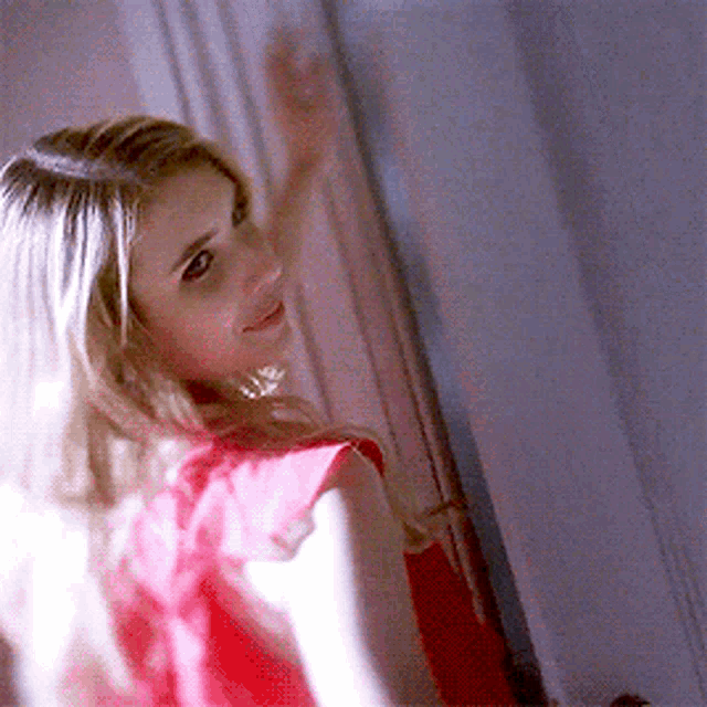 a woman in a red dress is smiling and waving