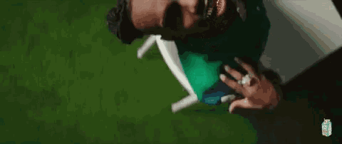a man in a green shirt is sitting in a white chair on a lawn .