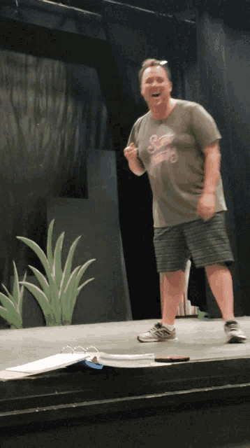 a man standing on a stage wearing a shirt that says ' swamp thing '