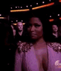 a woman in a white dress is standing in front of a crowd of people in a dark room .