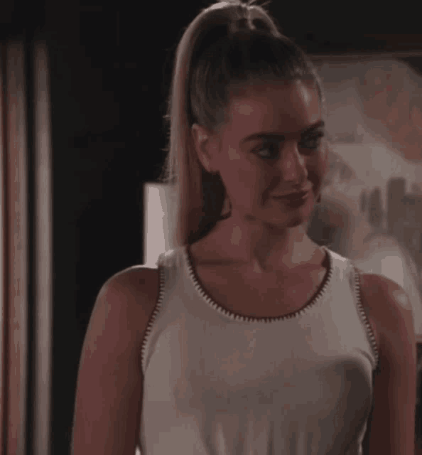a woman with her hair in a ponytail is wearing a tank top