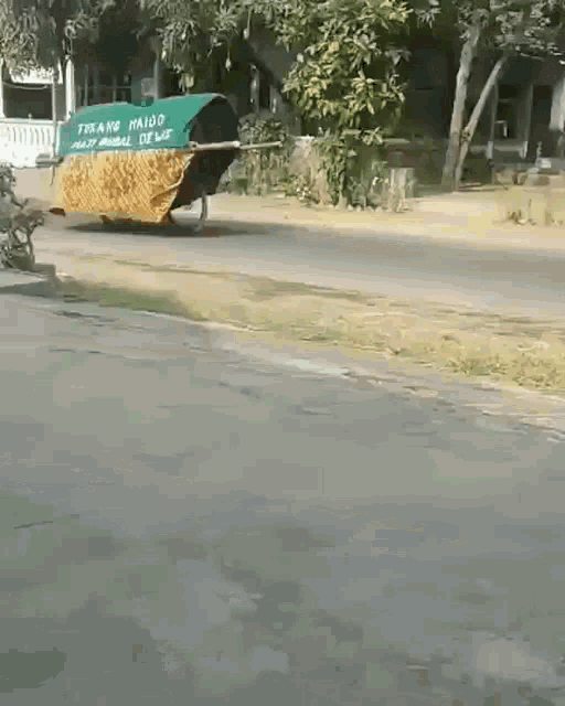 a green tarp that says ' tirang maido ' on it is being pulled by a person