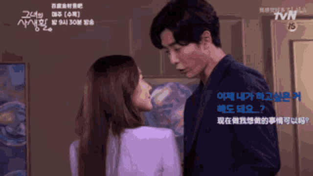 a man and a woman are kissing in front of a tvn sign