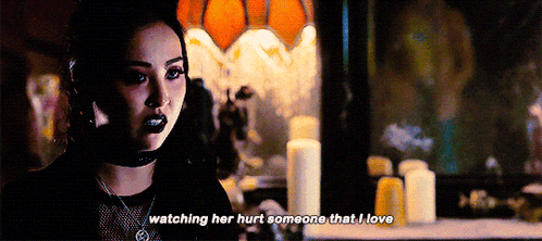 a woman is standing in front of a mirror with candles and says watching her hurt someone that i love