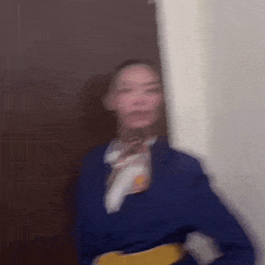 a blurry picture of a woman in a blue suit and scarf standing next to a door .