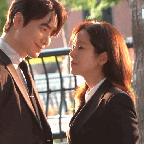 a man in a suit and tie looks at a woman in a suit