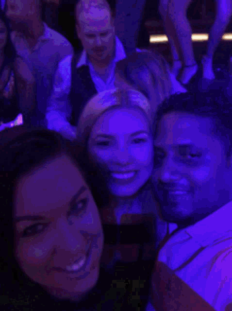 a man and a woman are posing for a picture in a crowded room