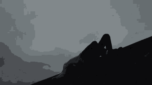 a person is laying on the roof of a building in the dark .