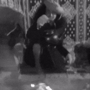 a black and white photo of a person sitting on a couch with a striped rug .