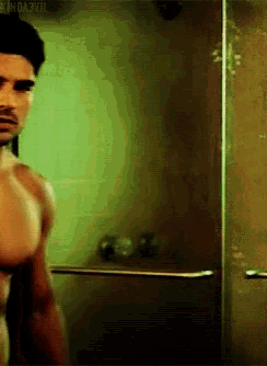 a man without a shirt is standing in a shower with the words sin dazzle behind him