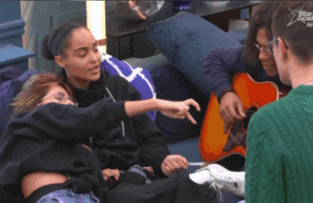 a group of people sitting on a couch with a man playing a guitar and a woman pointing