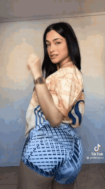a woman in a tie dye shirt and blue shorts is dancing .