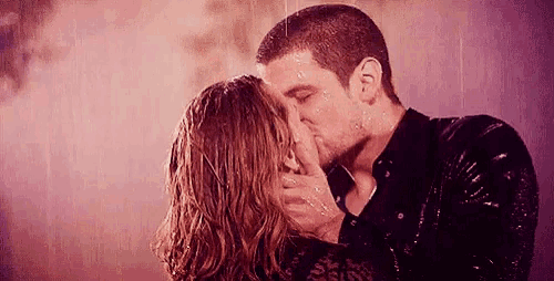 a man and a woman are kissing in the rain .