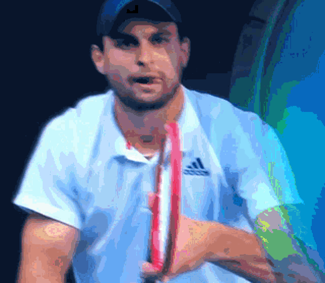 a man wearing an adidas shirt holds a tennis racquet