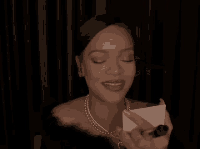 a woman in a black dress is smiling while holding a box .