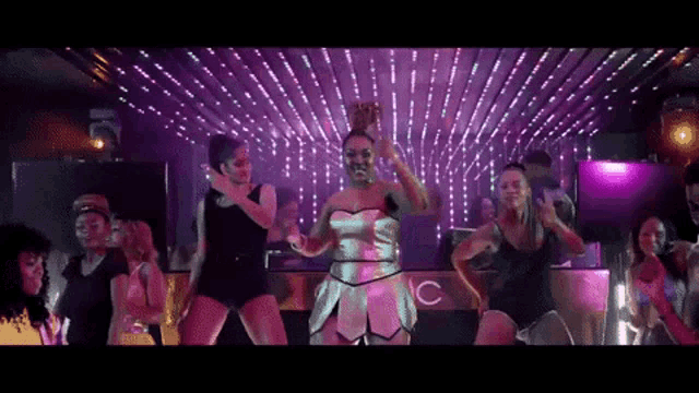 a group of women are dancing in a club with a sign that says c.