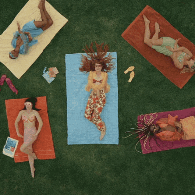 a group of people are laying on towels in a circle