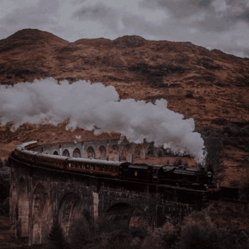 a train is going over a bridge in the mountains