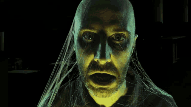 a man with a beard is covered in a spider web with his mouth open