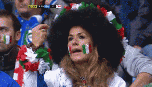 a woman wearing a large afro wig is watching a soccer game with a score of 1 to 1