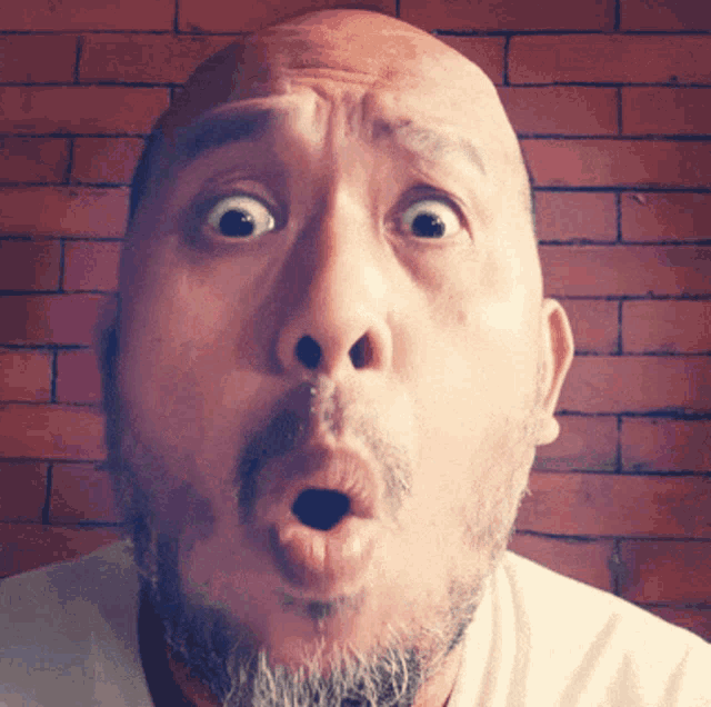 a bald man with a beard makes a surprised face