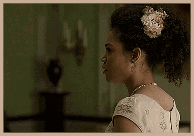 a woman with curly hair has a flower in her hair and earrings