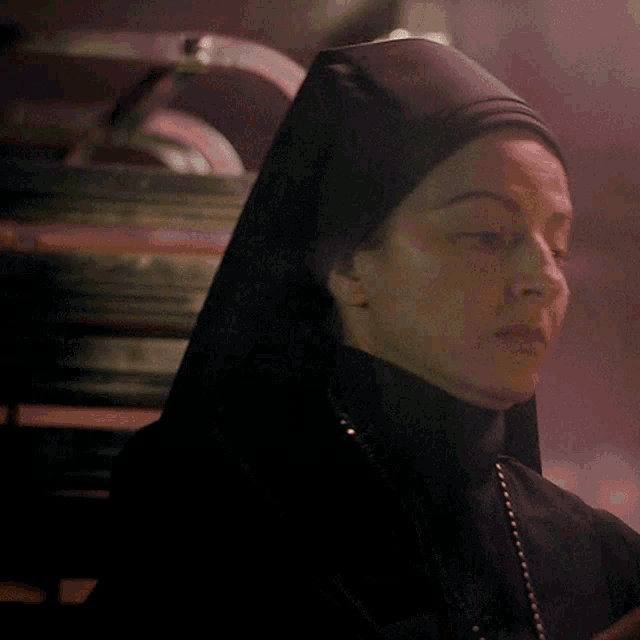 a woman in a nun 's veil is looking at something