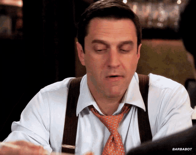 a man wearing suspenders and an orange tie with barbabot written on the bottom right
