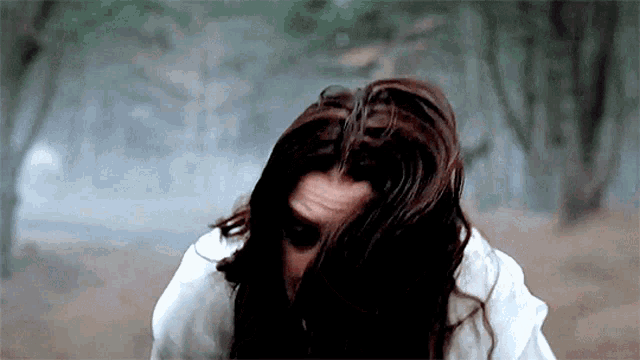 a woman with long dark hair covering her face with her hair