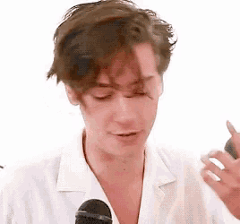 a man in a white shirt is holding a microphone in front of his face .