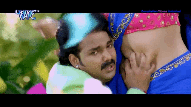 a man is touching a woman 's belly in a video that says wave on the bottom
