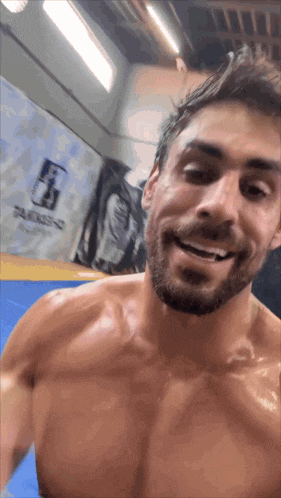 a man without a shirt is smiling in front of a wall that has the letter f.