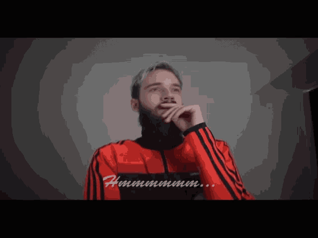 a man with a beard wearing a red and black adidas jacket
