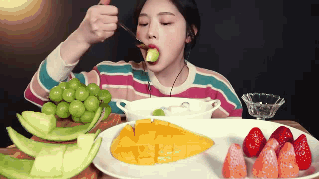 a woman is eating a piece of fruit with a spoon in her mouth